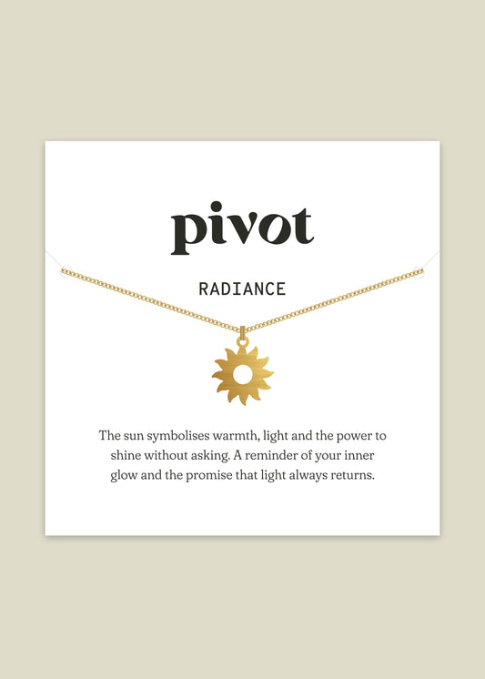 Gold necklace with sun pendant on a white card with text about the symbol of the sun.